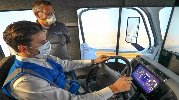 SBVC professor Berchman “Kenny” Melancon observes as Enrique Allen Mar of Advanced Training Systems demonstrates a commercial truck driving simulator the college is acquiring as part of its expanded clean vehicle technology curriculum.