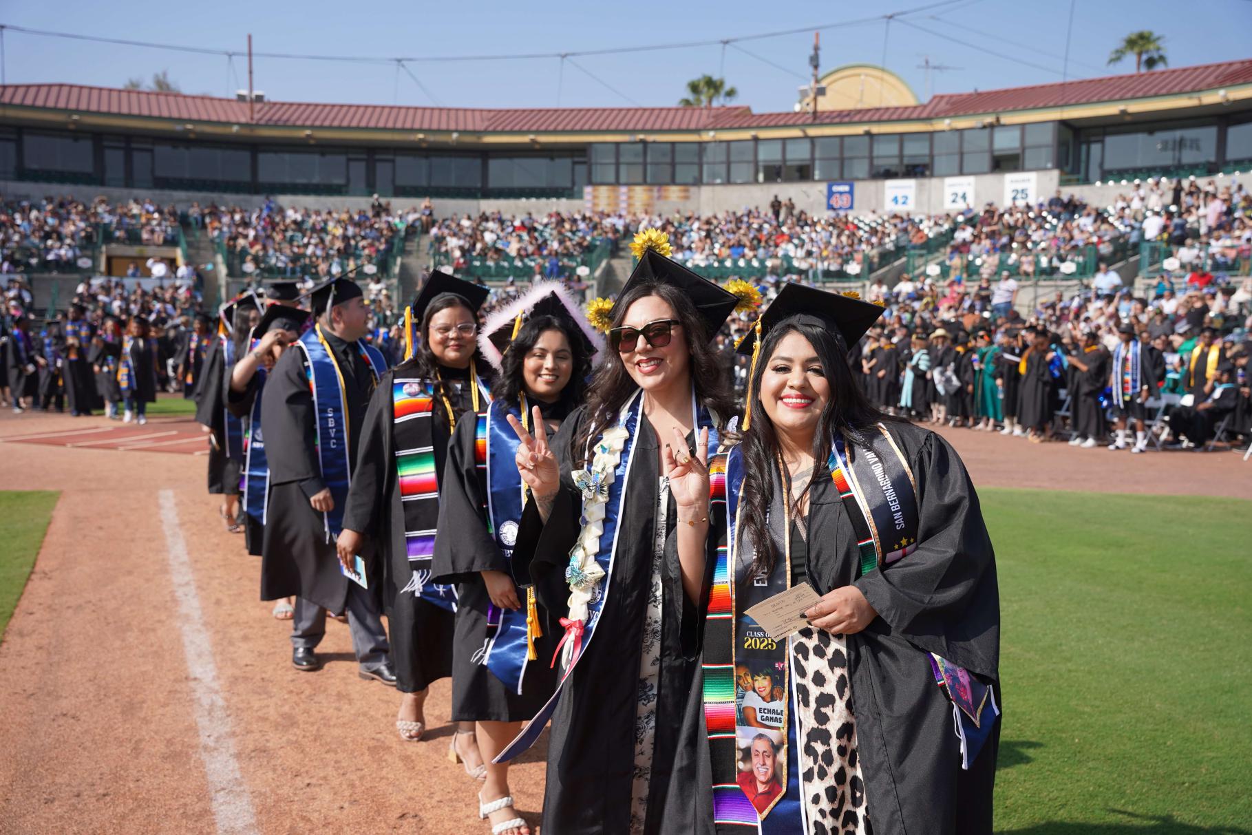 Graduates lined up giving the "valley up" peace sign