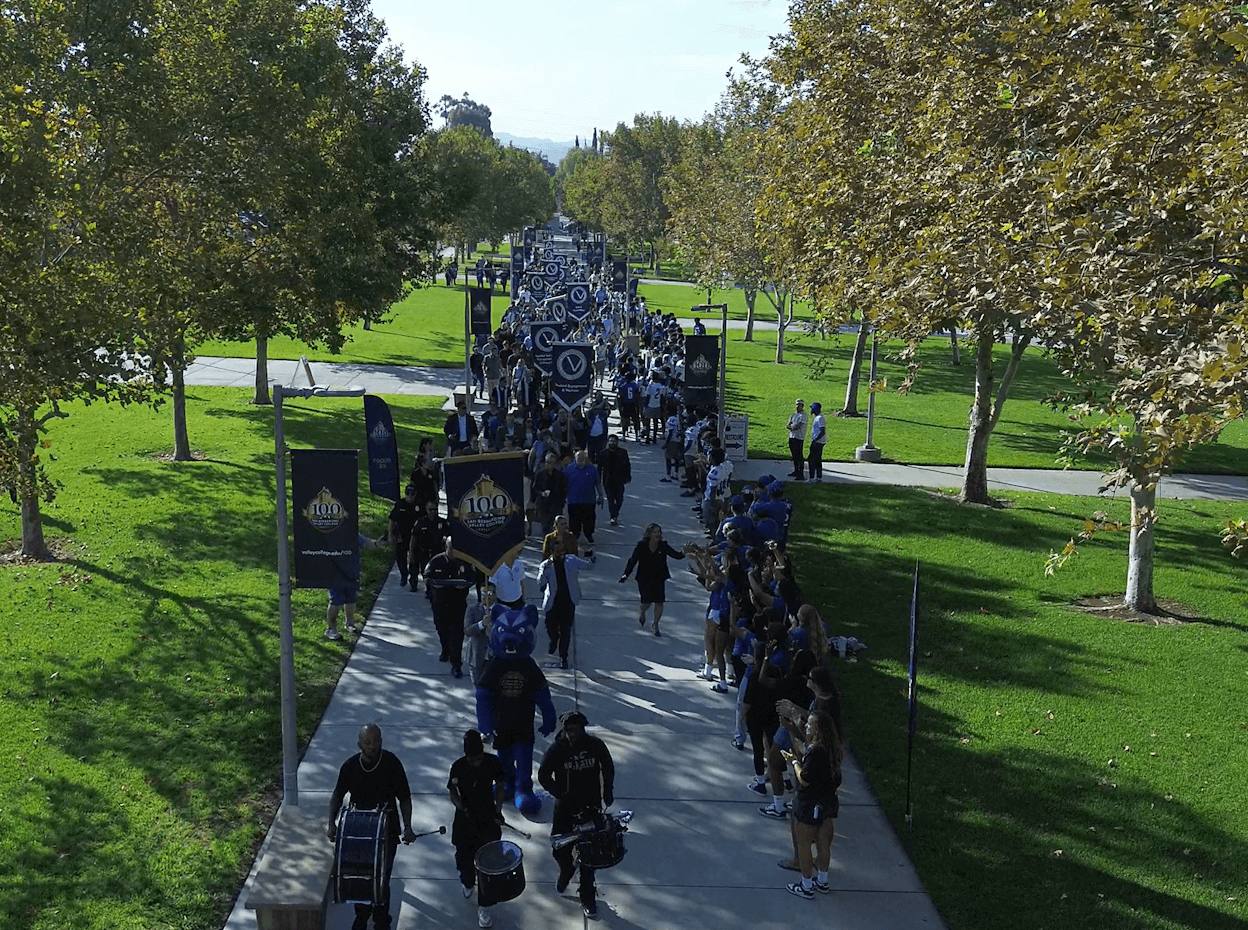 A procession of SBVC faculty & staff heading down Campus Center Walkway accompanied by drumline and SBVC athletes