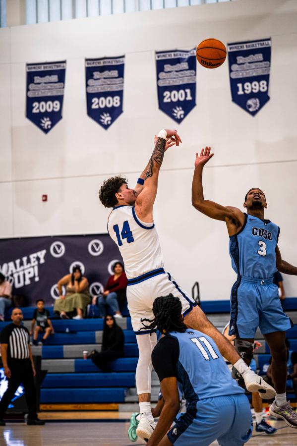 An SBVC basketball player shooting with two Cerro Coso College players defending